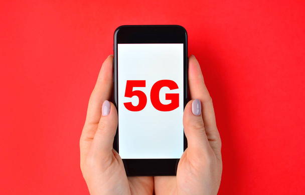 5G generation wireless system concept with hands and smartphone on a red background. - Foto, Imagem