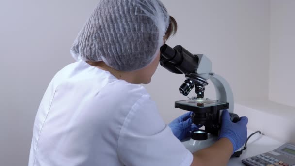 Woman chemist in the laboratory works with a microscope - Footage, Video