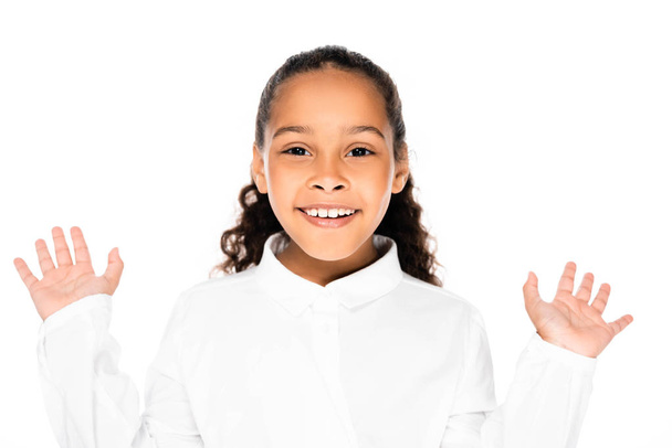 cheerful african american schoolgirl gesturing and smiling at camera isolated on white - Photo, image