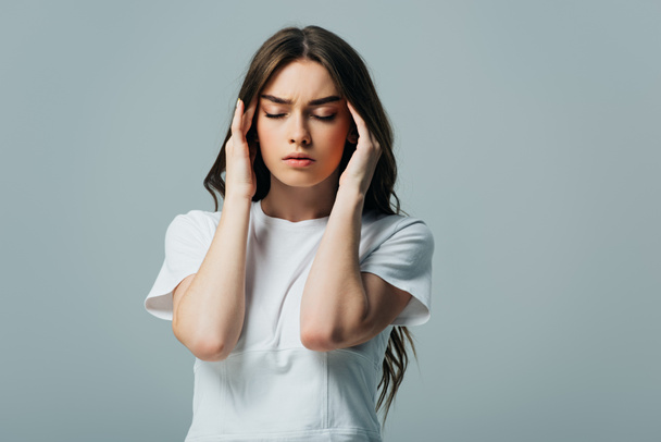 tense beautiful girl in white t-shirt with closed eyes suffering from migraine isolated on grey - Fotoğraf, Görsel
