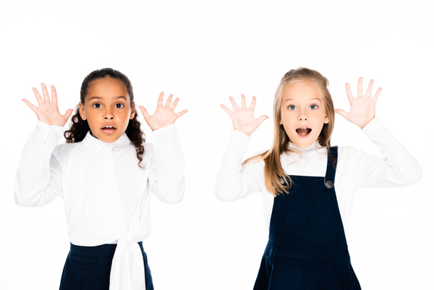 zwei überraschte multikulturelle Schulmädchen, die kreidebefleckte Hände zeigen, isoliert auf weiß - Foto, Bild