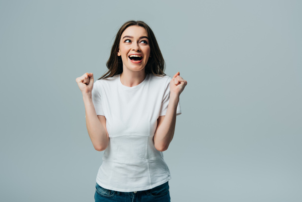 excited beautiful girl in white t-shirt showing yes gesture and looking away isolated on grey - Fotoğraf, Görsel