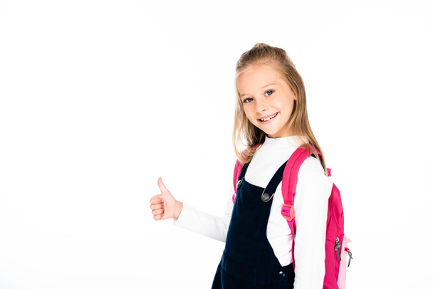 cheerful schoolgirl showing thumb up while smiling at camera isolated on white - Foto, imagen