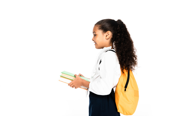 sırt çantası beyaz izole kitaplar tutan afrikalı amerikalı kız öğrencinin yan görünümü - Fotoğraf, Görsel