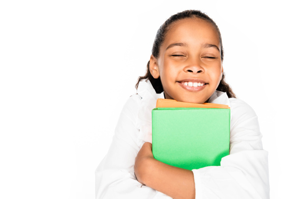 szczęśliwy Afrykański amerykański uczennica uśmiecha się z zamkniętymi oczami trzymając książki odizolowane na biały - Zdjęcie, obraz