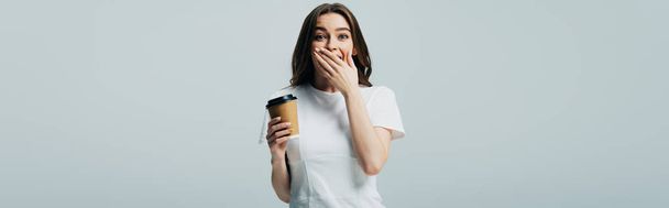 surprised beautiful girl in white t-shirt with paper cup isolated on grey, panoramic shot - Photo, Image