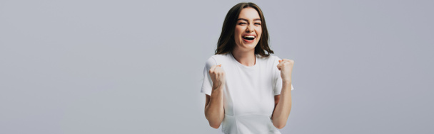 schockiert glücklich schönes Mädchen in weißem T-Shirt berühren Gesicht isoliert auf grau - Foto, Bild