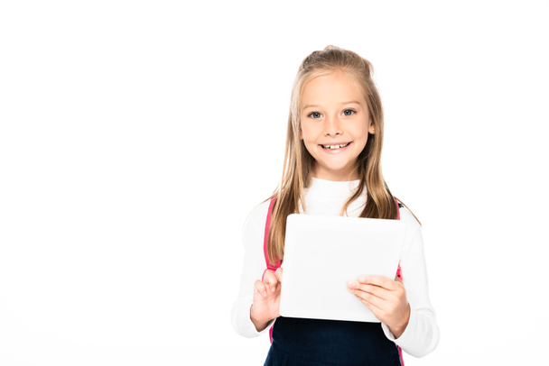 adorable schoolgirl halding laptop and smiling at camera isolated on white - Foto, afbeelding