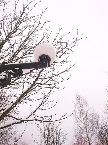 Téli séta egy kis európai faluban a hegyekben. A házakat és padokat hó borítja. - Fotó, kép