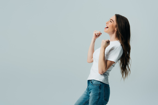 side view of happy beautiful girl in white t-shirt showing yes gesture isolated on grey - Photo, Image