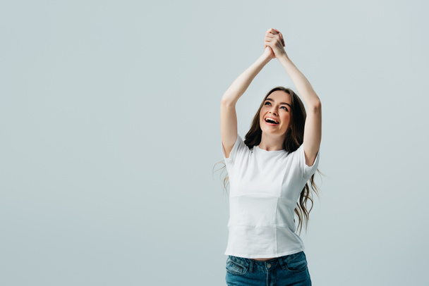 happy beautiful girl in white t-shirt with praying hands isolated on grey - Фото, изображение