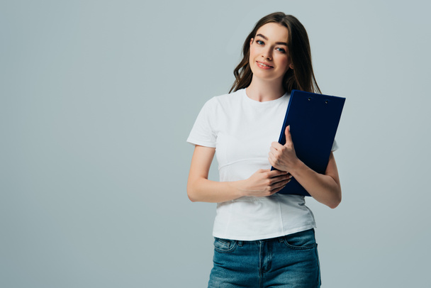 happy beautiful girl in white t-shirt holding clipboard isolated on grey - Foto, immagini