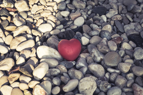 lonely red heart with drops of water lies on a stone beach, conc - Photo, Image