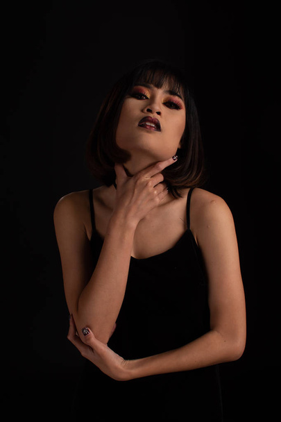 Southeast asian woman with dark tone makeup on black background, - Фото, изображение