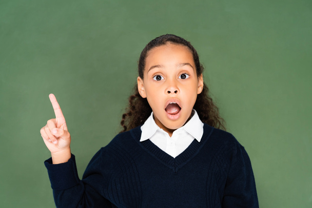 shocked african american schoolgirl showing idea gesture while standing near green chalkboard - Zdjęcie, obraz