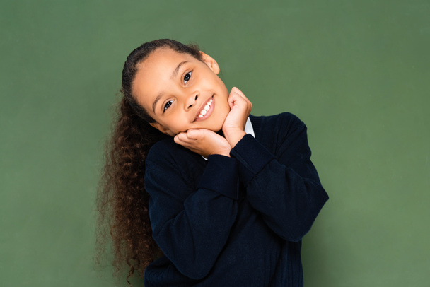 boldog afroamerikai iskoláslány kezében kéz közelében arc állva közel zöld palatboard - Fotó, kép