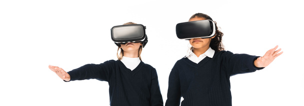 panoramic shot of two multicultural schoolgirls using virtual reality headsets isolated on white - Zdjęcie, obraz