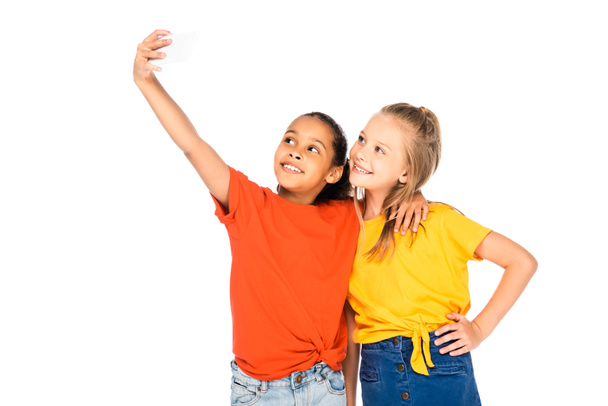 vrolijk Afrikaans-Amerikaans kind dat selfie neemt met lachende vriend geïsoleerd op wit - Foto, afbeelding