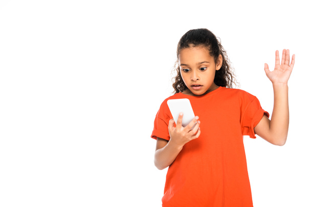shocked african american kid gesturing while using smartphone isolated on white - Fotografie, Obrázek