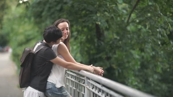 Couple in love lesbians standing on bridge in the green park, Beautiful lesbians kissing in lips and talking, video  - Materiał filmowy, wideo