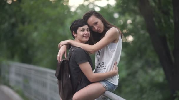 lesbian couple on bridge fence looking at camera, video - Materiał filmowy, wideo