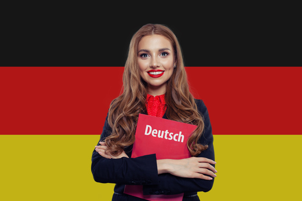 Portret van gelukkige jonge vrouw glimlachend tegen de vlag van Duitsland  - Foto, afbeelding