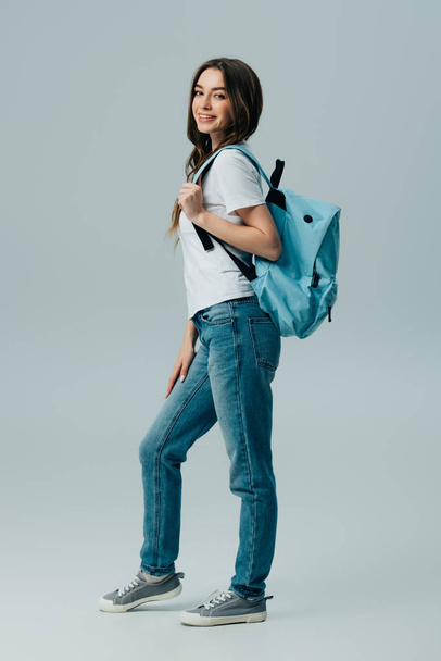gri izole mavi sırt çantası ile güzel gülümseyen kız tam uzunlukta görünümü - Fotoğraf, Görsel