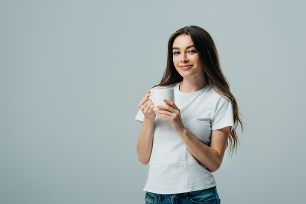 smiling girl in white t-shirt holding white mug isolated on grey - 写真・画像