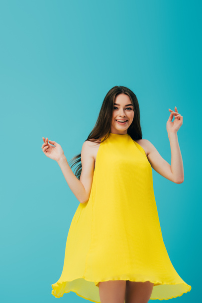 happy beautiful girl in yellow dress spinning around isolated on turquoise - Фото, зображення