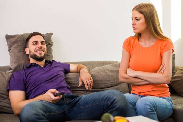Angry wife and husband are having conflict because husband is watching tv too much. - Фото, изображение