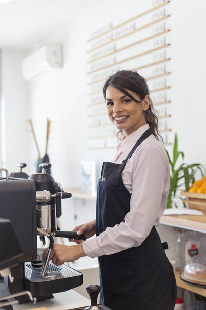 Beautiful women barista smiling and using coffee machine in coffee shop  - Photo, image