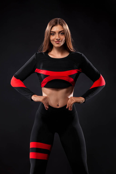 Strong athletic woman , posing on black background wearing in sportswear. Fitness and sport motivation. Copy space. - Фото, зображення