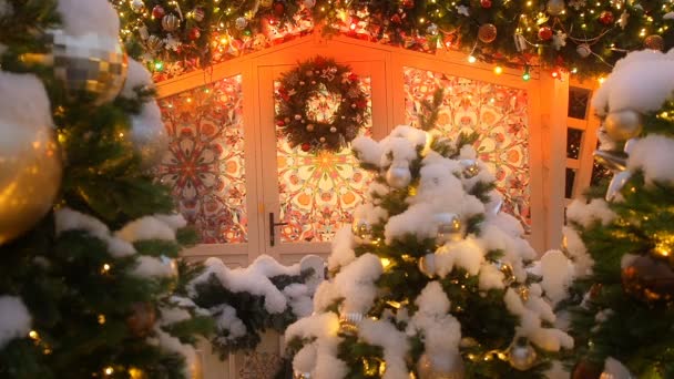 Kerst FIR krans opknoping op de deur van een prachtig huis met ornamenten op de ramen en kerst Garland versierd met kerstballen en lichten aan de bovenkant. -mooie seizoensachtergrond - Video