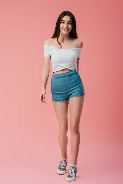 full length view of smiling girl isolated on pink - Foto, afbeelding