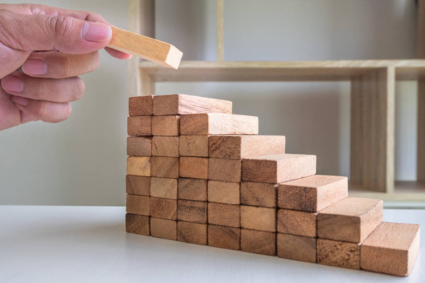 Εικόνα του χεριού κρατώντας μπλοκ παιχνίδι ξύλου για την ανάπτυξη της επιχείρησης. Κίνδυνος διαχείρισης και στρατηγικού σχεδίου - Φωτογραφία, εικόνα