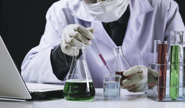Pesquisador com tubos de ensaio químicos de laboratório de vidro com líquido
 - Foto, Imagem