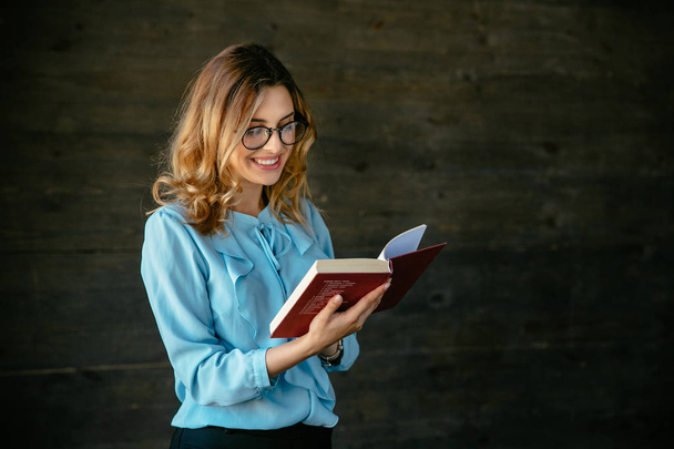 Cheerful attractive woman reading interesting book - Foto, afbeelding