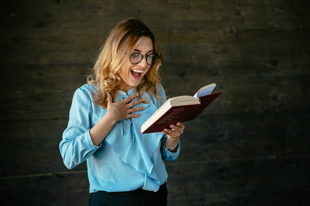 Smiling woman in eyeglasses reading interesting book - Fotoğraf, Görsel
