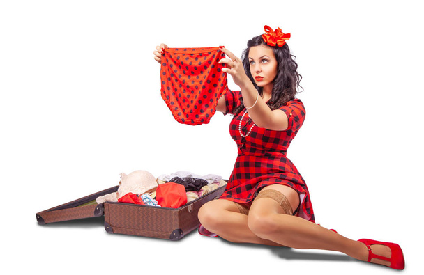 jovem mulher sentada no chão e colocando roupas em uma suitca
 - Foto, Imagem
