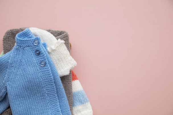 Cute knitted baby clothes layout on a pastel pink background - Valokuva, kuva