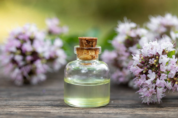 Бутылка эфирного масла с цветущим орегано
 - Фото, изображение