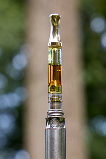 Marijuana oil for vaping on blurred natural background. - Photo, Image