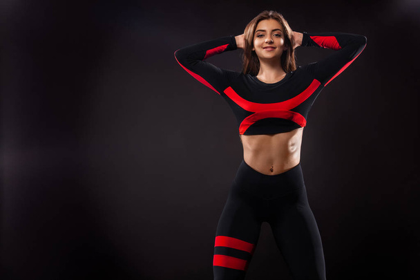 Strong athletic woman , posing on black background wearing in sportswear. Fitness and sport motivation. Copy space. - 写真・画像