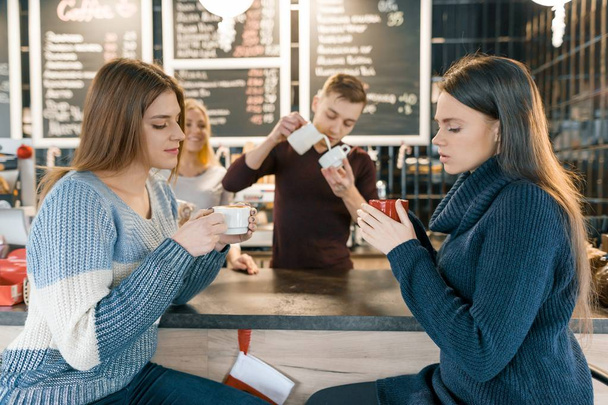 Young women drinking coffee in cafe, girls sitting near the bar counter - Фото, зображення