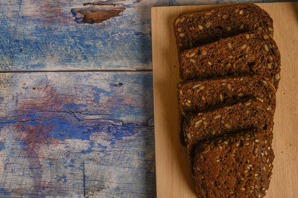 Pan de grano rebanado en una tabla de madera. Almuerzo en estilo rústico
. - Foto, imagen