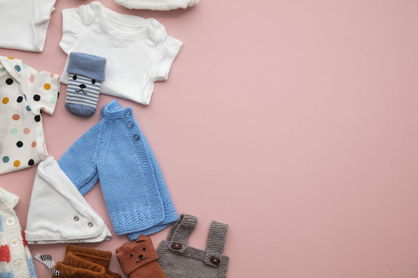 Cute baby clothes layout on a pastel pink background - 写真・画像
