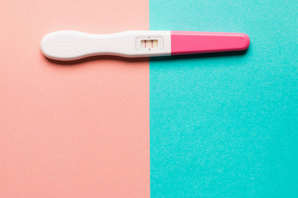 ピンクと青の背景に肯定的なピンクのプラスチック妊娠テスト - 写真・画像