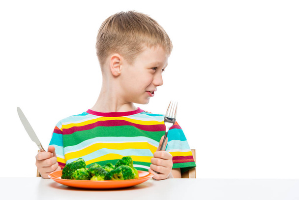 portrait of a boy with a plate of tasteless broccoli on a white  - Photo, Image