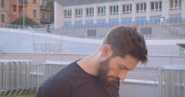 Closeup portrait of adult caucasian sporty male jogger walking on the stadium in the urban city outdoors - Footage, Video