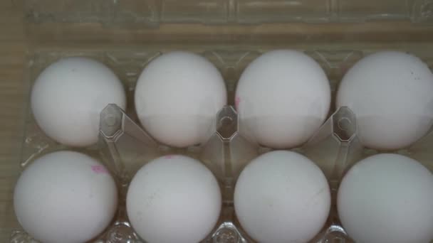 Box of white eggs in box and painted colorful Easter eggs in dish - Video